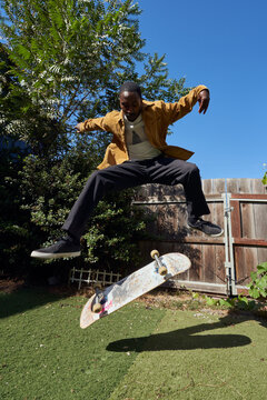 Portrait of young non-binary doing flip tricks on skateboard 
