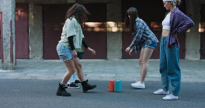 Cheerful girls put their portable music speakers of color against each other. Street dance battle among neighborhood garages of two teenage girl duos.