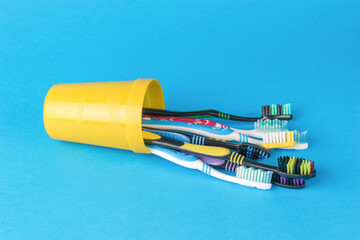 A fallen glass with multicolored toothbrushes on a blue background.