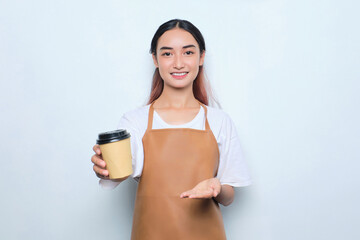 Cheerful pretty young barista girl in apron giving to client takeaway cup of coffee isolated on white background