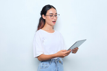 Portrait of shocked young Asian girl in white t-shirt using digital tablet isolated on white background