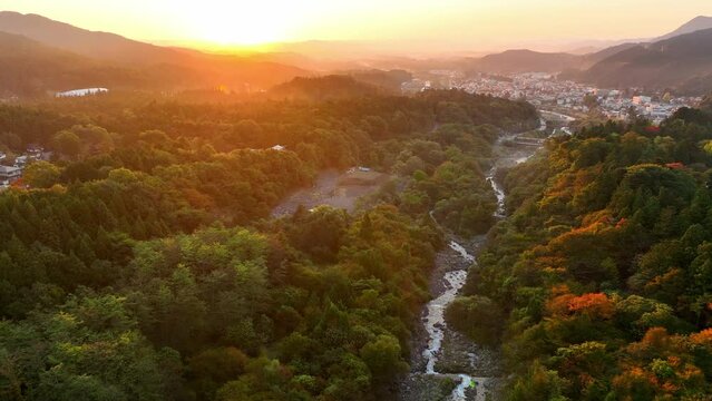autumnal Japanese mountain landscape in Nikko at sunrise, flying above autumn forest and river in the mountains at dawn in Japan