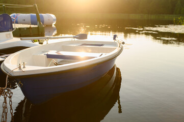Fototapeta na wymiar Empty blue and white boat on the water at sunset.Water recreation concept