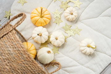 Obraz na płótnie Canvas Sweet mini pumpkins and a garland of stars tumbled out of a wicker basket onto a blanket in a vortex of leaves. Thanksgiving day decor.