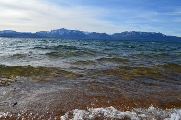 Waves at Lake Tahoe with snowcapped mountains in the background. 