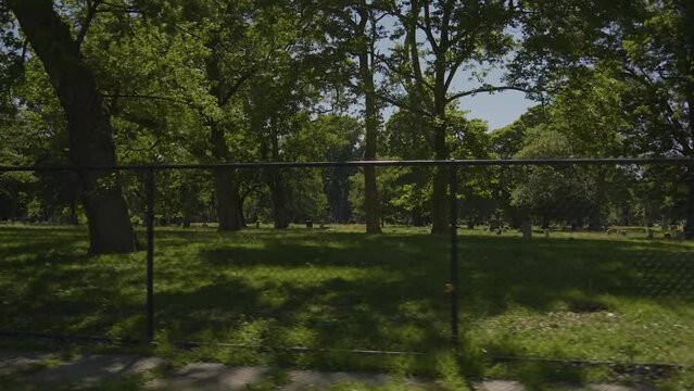Panning shot of fence with Lake View Cemetery in the background on a sunny summer day.