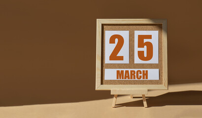 March 25th. Day 25 of month, Calendar date. Cork board, easel in sunlight on desktop. Close-up,...