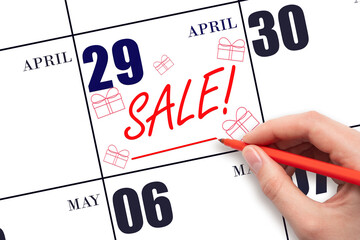 Hand writing text SALE and drawing gift boxes on calendar date April 29. Shopping Reminder
