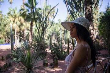 Beautiful tourist with hat visiting the Berber Majorelle garden which is a botanical garden in Marrakech (Morocco) that was designed by the French expatriate artist Jacques Majorelle.