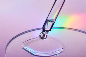 Pipette with sample of cosmetic product in petri dish on holographic background, iridescent...