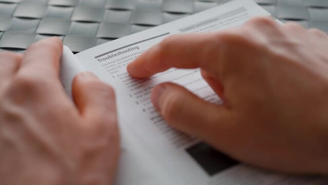 Man reading the user manual of a tv. Troubleshooting section. Close up
