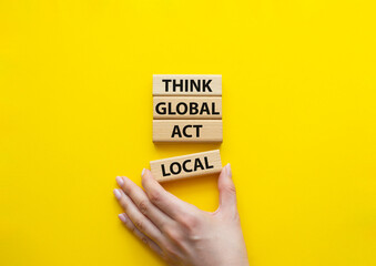 Think global act local symbol. Wooden blocks with words Think global act local. Beautiful yellow background. Businessman hand. Business and Think global act local concept. Copy space.