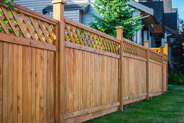 Nice new wooden fence around house. Wooden fence with green lawn. Street photo - Powered by Adobe