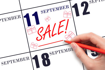 Hand writing text SALE and drawing gift boxes on calendar date September 11. Shopping Reminder