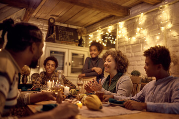 Happy black extended family talking while celebrating Thanksgiving at dining table.
