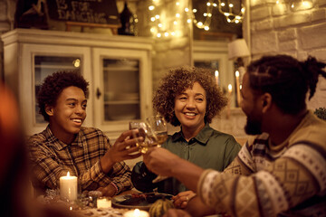 Happy black multigeneration family toasting during Thanksgiving dinner at dining table.