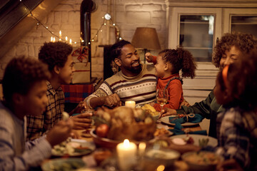Happy black multigeneration family enjoying in lunch while celebrating Thanksgiving at dining table.