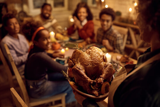 Close Up Of Grandmother Serving Thanksgiving Turkey For Family Dinner In Dining Room.