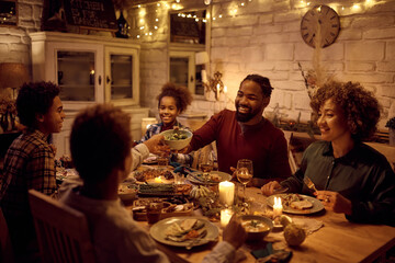 Happy black man having Thanksgiving dinner with his extended family at dining table.