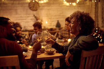 Happy mature black woman and her son toasting during family lunch on Thanksgiving.