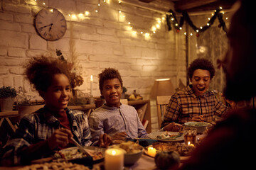 Happy black kids enjoying in family dinner at dining table on Thanksgiving.