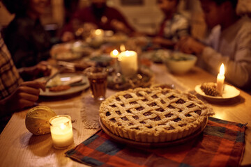 Close up of sweet pie on dining table with African American family in the background on Thanksgiving.