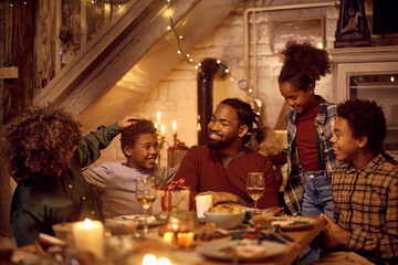 Happy African American extended family talking at dining table during Thanksgiving dinner.