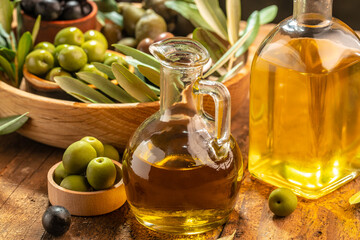 olives berries in wood bowls and pressed oil in glass bottles on a wooden background. place for text