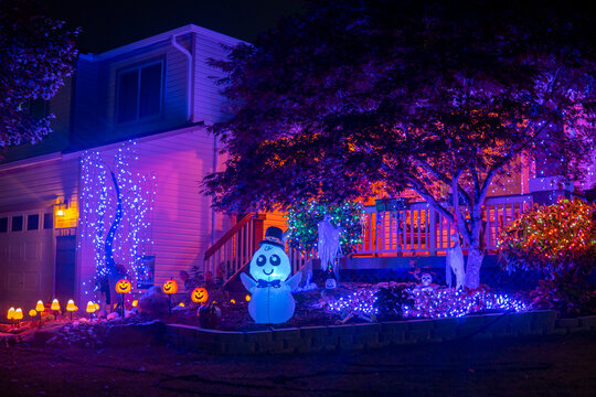 Illuminated night Halloween house outdoor decorations with colorful lights, lanterns, monsters and glow garlands