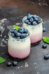 Homemade dessert Panna cotta with blueberry berries and jelly in jars on a dark background. Delicious balanced food concept. place for text, top view
