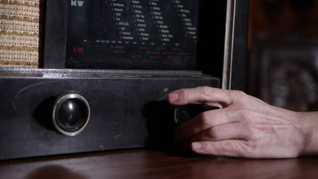 Listening to music concept, old style, fm channel is playing music, stylish retro radio player stands, hand turns on radio close-up, vintage background with retro broadcast radio receiver circa 1950