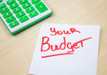 YOUR BUDGET text on sheet by red marker next to calculator on chalkboard