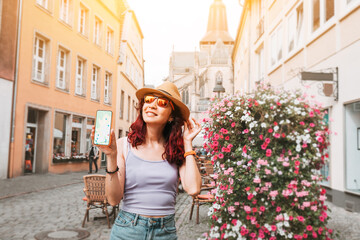 A tourist girl with a smartphone on the screen of which is an application with maps and geolocation on the streets of an old European city