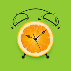 Fresh orange fruit and drawn alarm clock on green background
