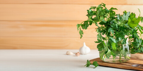 Glass with bunch of fresh parsley on table. Banner for design