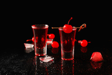 Delicious shot cocktails, cherries and ice cubes on dark background