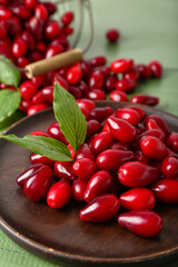 Plate with ripe red dogwood berries on color wooden table, closeup