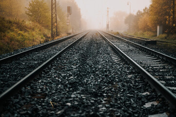 Naklejka na ściany i meble Railroad track rails in coutry landspace in autumn weather with foggy landscape. Industrial concept. Railroad travel, railway tourism.