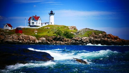 View of the waterside Nubble lighthouse on the grass under the blue sky