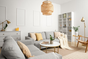 Interior of light living room with grey sofas, table and shelving unit