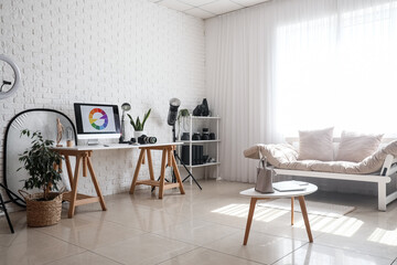 Interior of modern office with photographer's workplace, equipment and couch