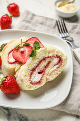 Plate with slices of sweet strawberry roll cake on table, closeup