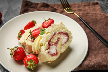 Plate with slices of delicious strawberry roll cake on table, closeup