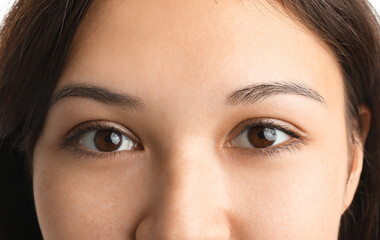 Young Asian woman with brown eyes on white background, closeup
