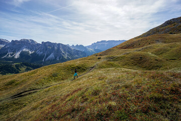 Sporty Young woman on mountain trail in Dolomites. Majestic view into the gardena valley
