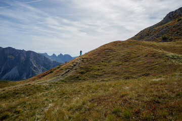 Sporty active young woman hiking on mountain ridge on a beautiful path in the dolomites. picturesque mountain scenery. gardena valley, alto adige, south tyrol, italy. travel and mountain scenery