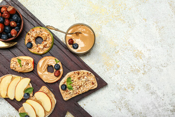 Wooden board of delicious sandwiches with nut butter and apples on light background