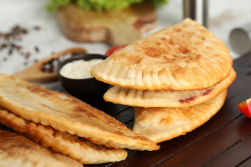Wooden board with tasty chebureks, closeup