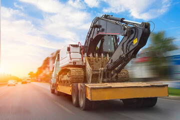 Transportation of a dirty excavator on a truck trailer after its work. Motion speed and blur effect...