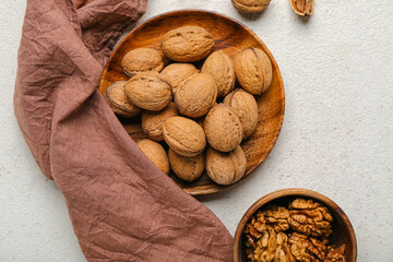 Plates with fresh walnuts on light background, closeup